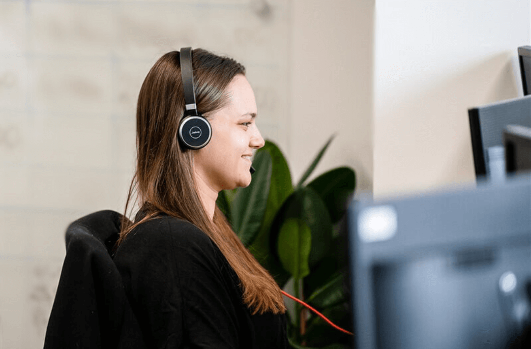 Woman smiling whilst speaking over a computer