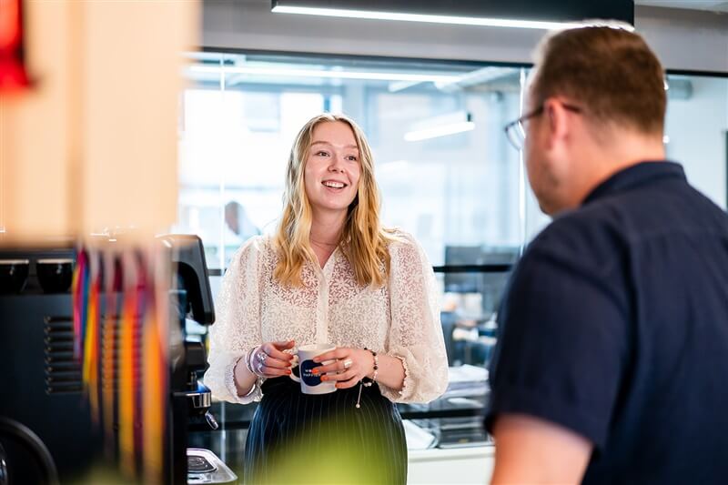 Man and woman talking over coffee in an office kitchen